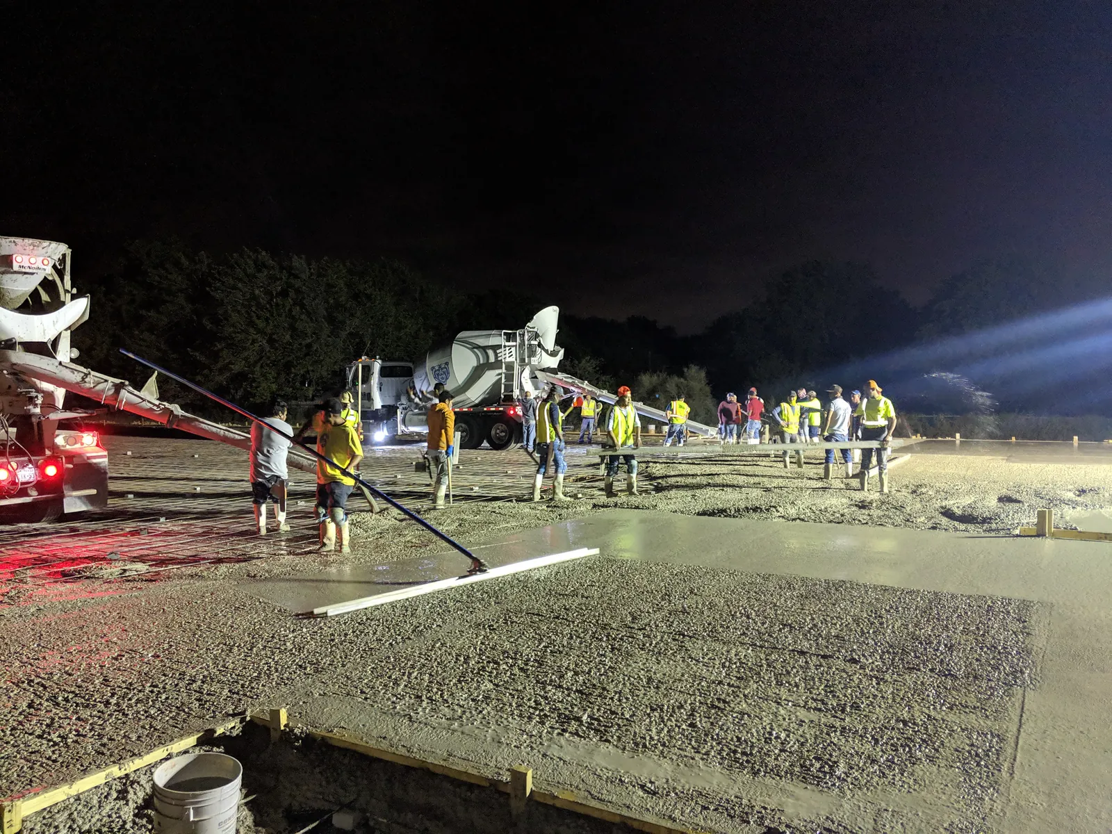 Crew screeding a large commercial slab under lights at night