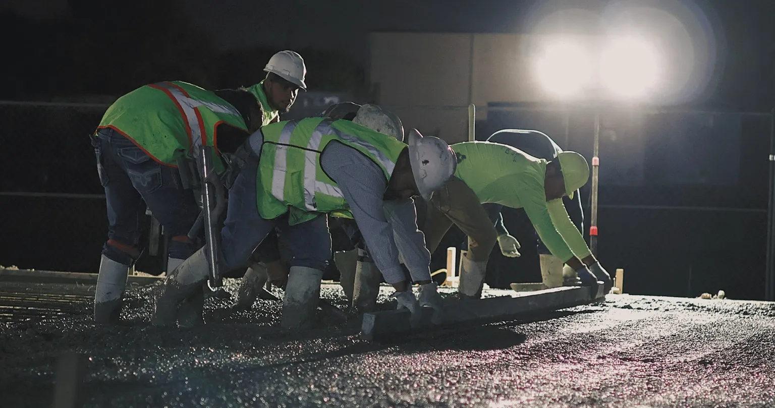Crew screeding a fresh slab under lights at night