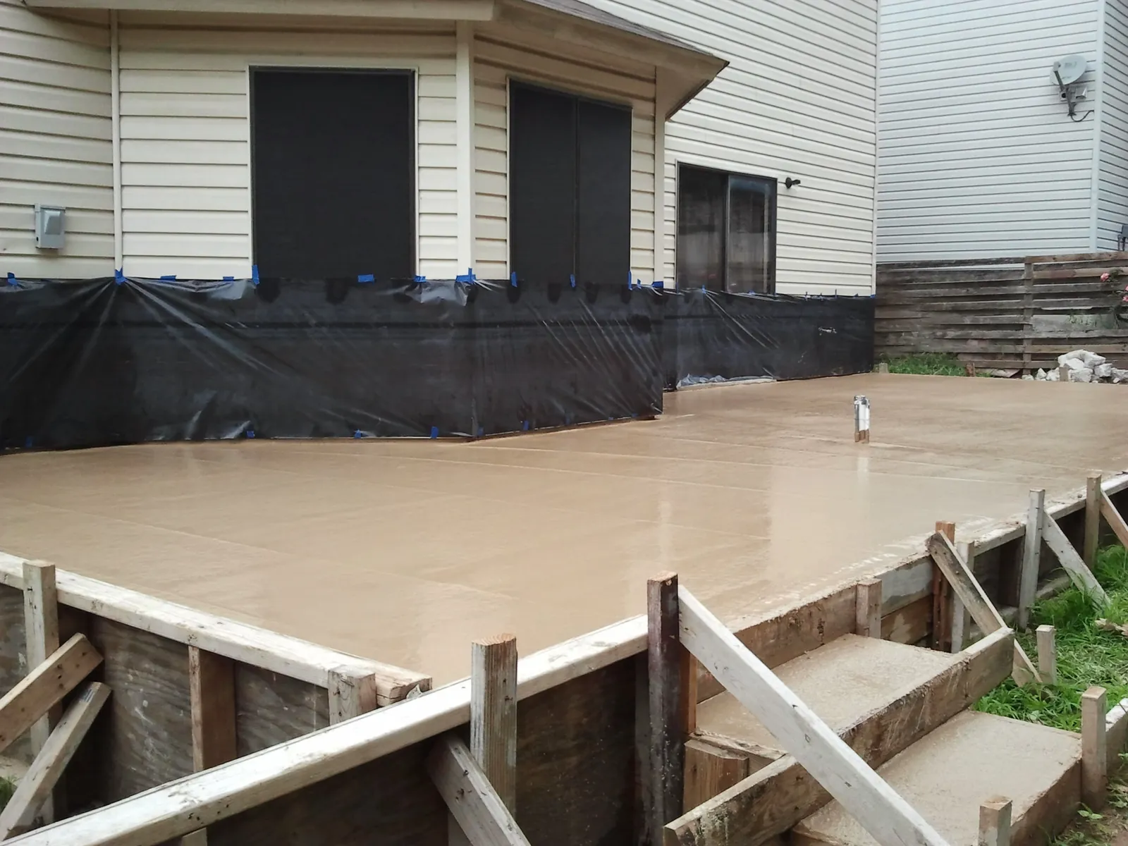 Freshly finished backyard patio slab behind a home